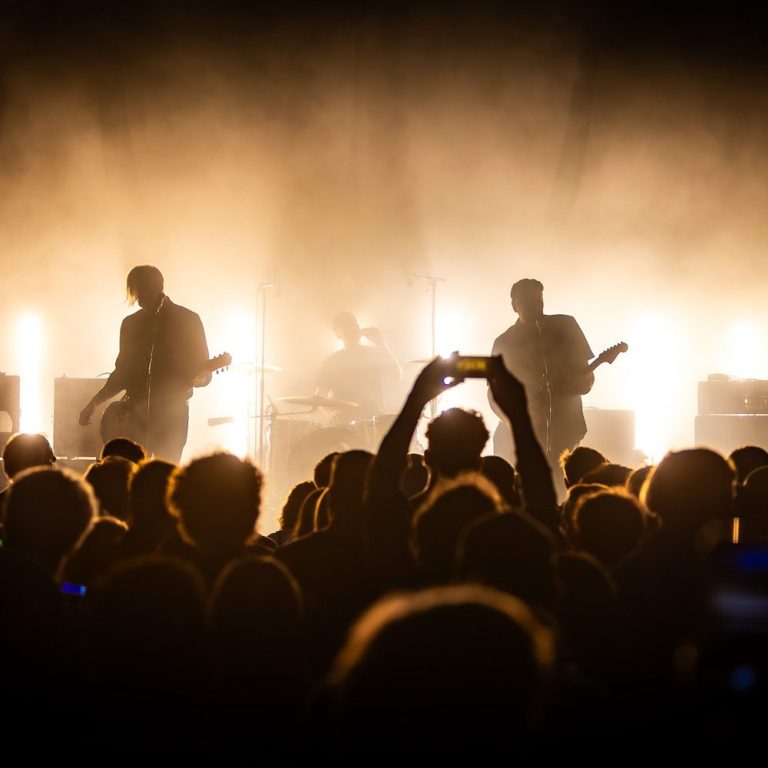 DRAMATIST live at Breminale Bremen Silhouetted band on stage with bright lights and crowd filming with phones.
