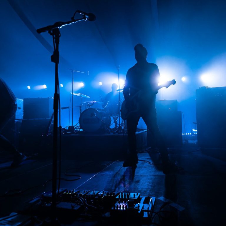 DRAMATIST live at Breminale Bremen Rock band silhouette on stage with blue lights and guitar in foreground.